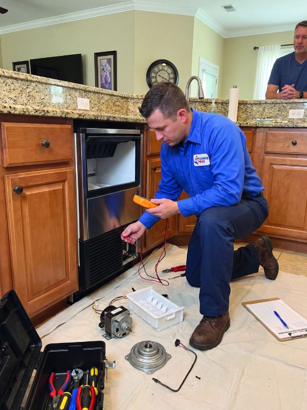 Appliance repair technician diagnosing a refrigerator ice maker for no-ice, slow production, and dispenser problems in a Lubbock, TX home